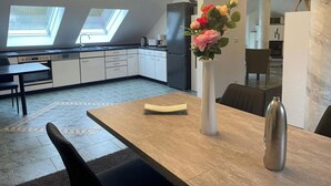 Una cocina moderna con tragaluces, un comedor con mesa y sillas, y un jarrón con flores.