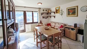 Un comedor acogedor con una mesa y sillas de madera, un sofá, y una zona de cocina con armarios y un lavamanos.