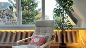 Una habitación moderna con una silla de respaldo de madera, un radiador y una planta en maceta.