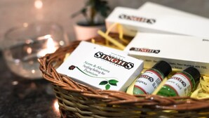 A wicker basket containing a box labeled "Singh's Neem & Aloe Vera Purifying Bathing Bar Premium," two bottles of shampoo, and a glass candle holder. - Hotel Singh's Vashi Navi Mumbai (Navi Mumbai)