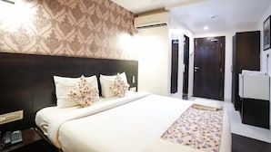 A hotel room with a large bed, a headboard, an air conditioning unit, a wardrobe, and a desk with a telephone. - Hotel Singh's Vashi Navi Mumbai (Navi Mumbai)