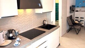 A modern kitchen with a black countertop, white cabinets, and a built-in stove. - Stunning private villa for 5 guests with A/C, TV and balcony (Villasimius)