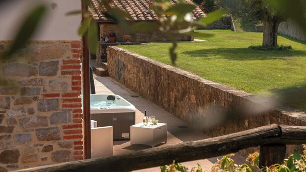 Een hottubgedeelte met stenen muren en een gazon.