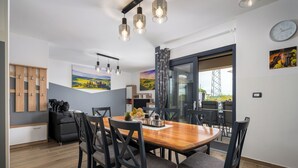 Un espace de salle à manger moderne avec une table en bois, des chaises noires et des luminaires suspendus.