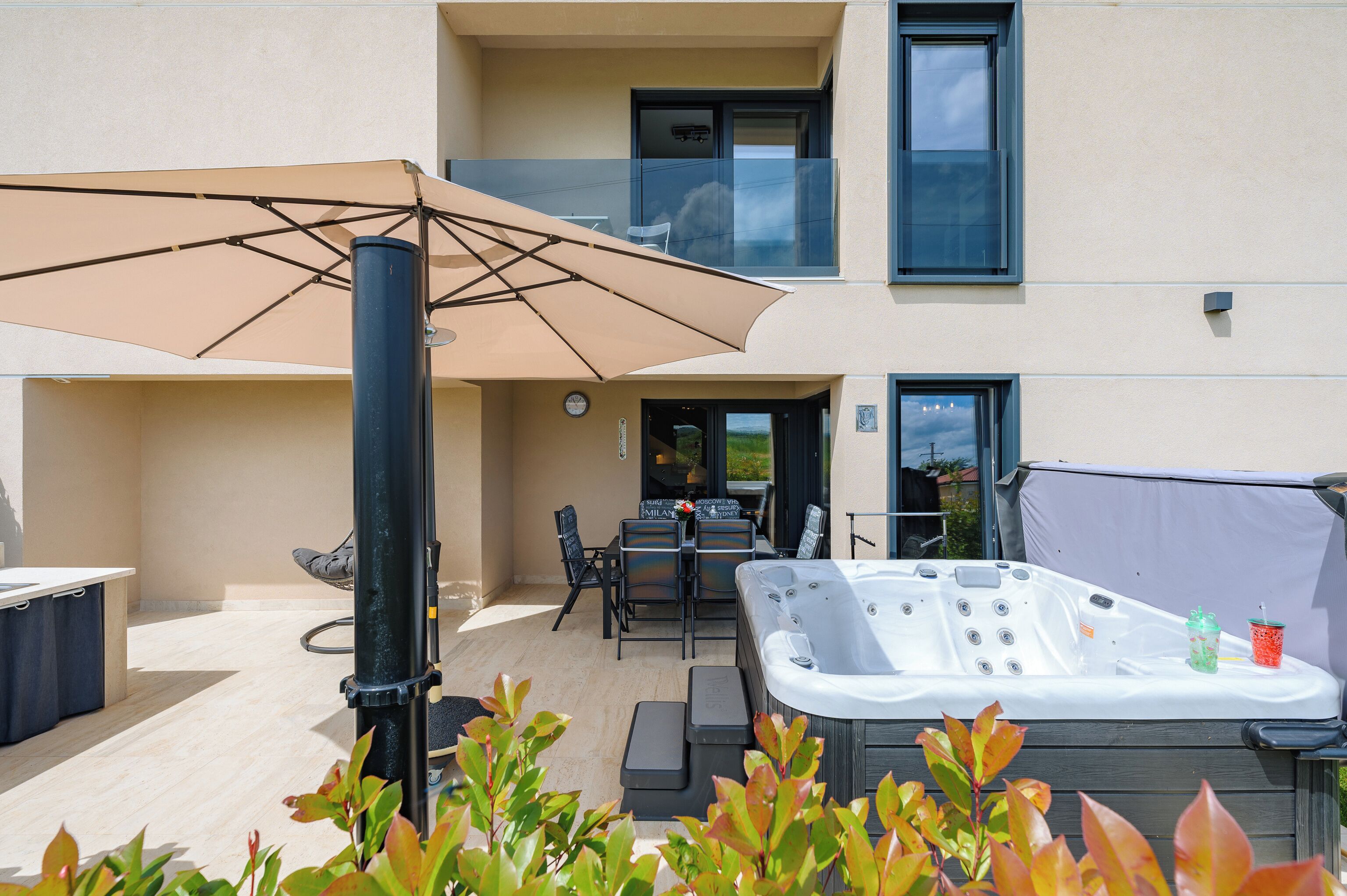 A spa area with a hot tub, outdoor seating, and a large umbrella.