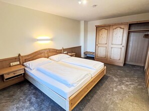 Una camera da letto con un letto in legno, comodini, un armadio e una lampada a parete.