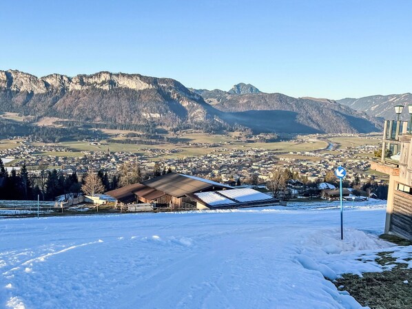 Paesaggio innevato con un paese nella valle e montagne sullo sfondo.