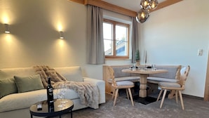 Ein gemütliches Wohnzimmer mit einer Couch, einem runden Holztisch mit Stühlen, einem kleinen Kaffeetisch und einem flauschigen Teppich.