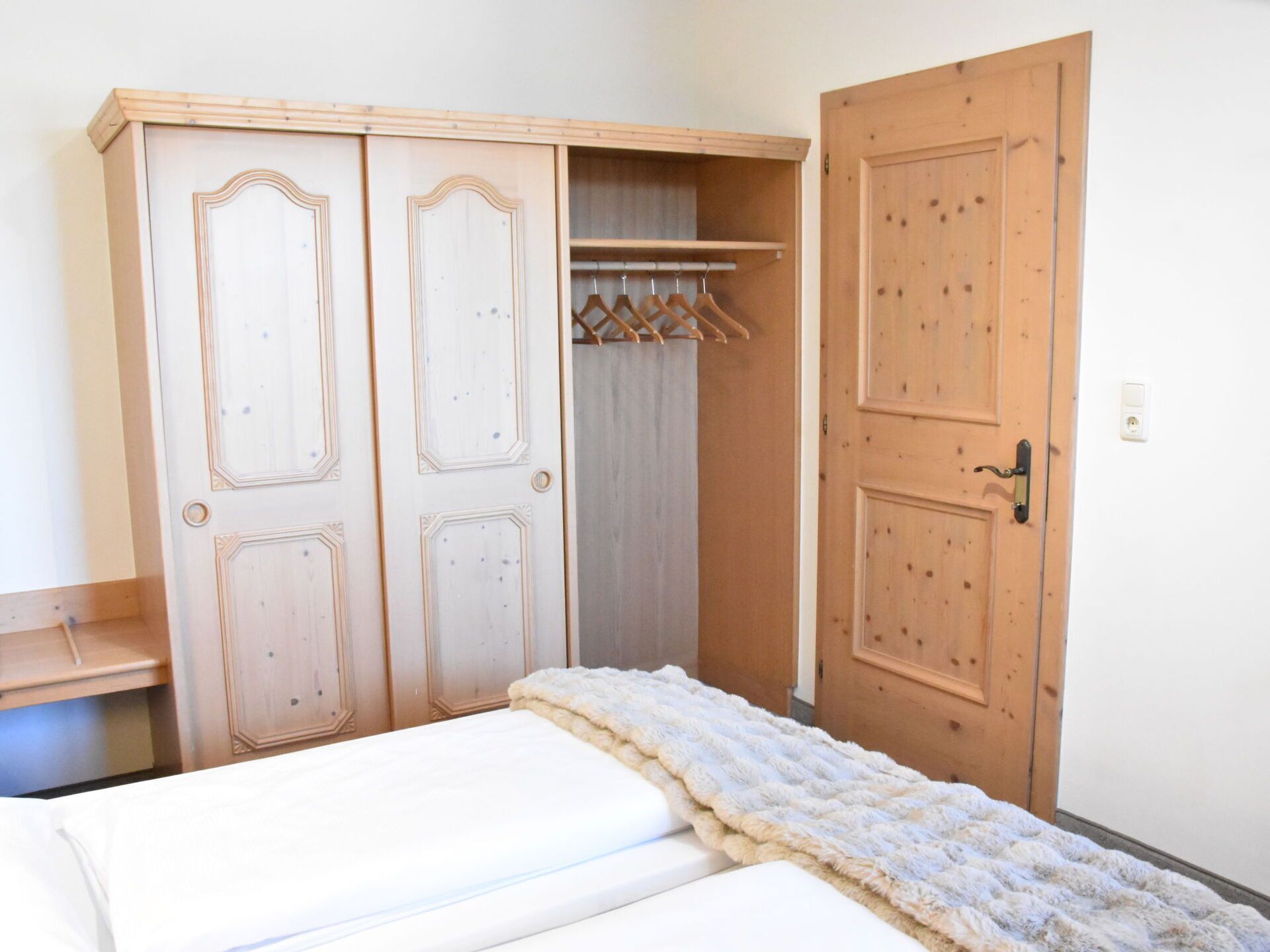 Et soveværelse med seng, garderobe og dør.