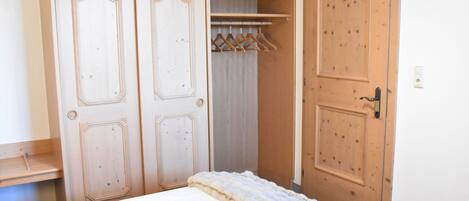Et soveværelse med seng, garderobe og dør.
