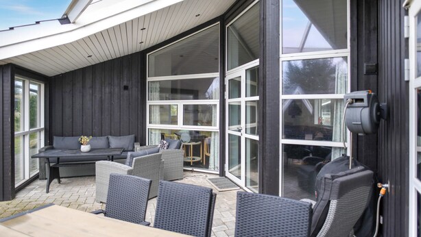 Un'area patio all'aperto con tavolo e sedie in legno, un divano e un piccolo tavolo rotondo con sedute.