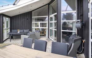 Un espace extérieur aménagé en terrasse, avec une table et des chaises en bois, un canapé et une petite table ronde avec des chaises.
