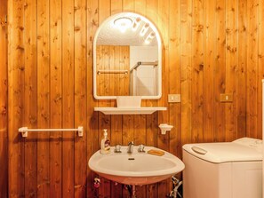 A wooden-paneled bathroom with a white sink, a mirror, a towel rack, and a toilet. - Nice apartment for 6 guests with WIFI, TV and patio (Dimaro)
