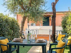 An outdoor dining area with a table set for two, surrounded by greenery and a building in the background. - Lovely apartment for 4 guests with WIFI, pool, A/C, TV, balcony and pets allowed (Viddalba)