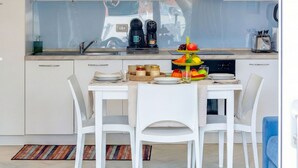 A modern kitchen with white cabinets, a dining table with chairs, and a coffee machine. - Beautiful apartment for 4 people with WIFI, pool, A/C, TV, balcony and pets allowed (Viddalba)