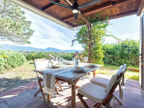 Ein Essbereich im Freien mit einem Tisch für zwei Personen, einem Deckenventilator und Blick auf die Berge.