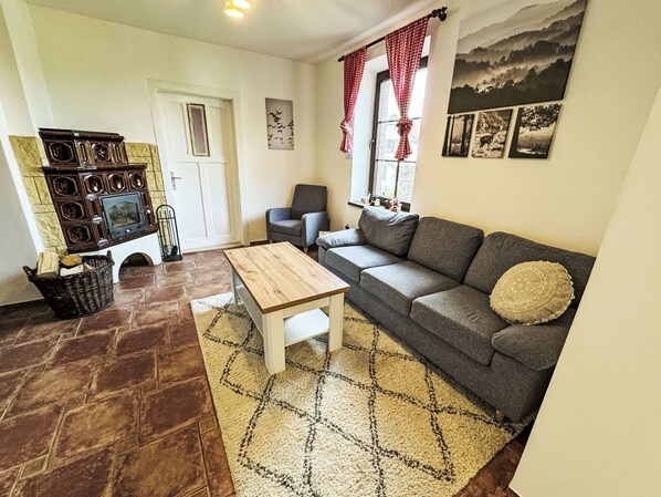 A cozy living room with a fireplace, a sofa, a coffee table, and a patterned rug.