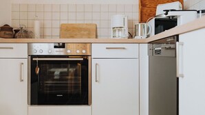 Een moderne keuken met witte kasten, een Siemens oven, een koffiezetapparaat en een vaatwasser.