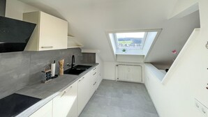 Eine moderne Küche mit Oberlichter, weißen Schränken und einer schwarzen Arbeitsplatte.