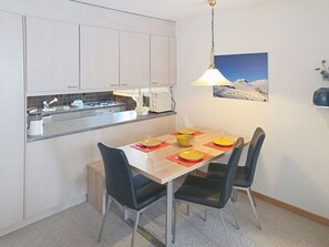 Una cocina compacta con comedor, microondas, lavamanos y un cuadro en la pared.