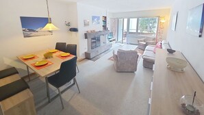 En moderne stue med spiseplads, pejs og udsigt gennem store vinduer.