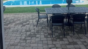 Un patio trasero con piscina, mobiliario de exterior y un asta con dos banderas.