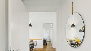 Ein Flur mit einer weißen Tür, einem runden Spiegel und einem Essbereich mit Tisch und Stühlen.