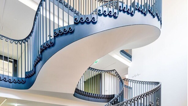 Eine moderne Wendeltreppe mit aufwendiger Metallgalerie in einem geräumigen, gut beleuchteten Innenraum.