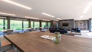 A spacious indoor area with a long wooden table, seating arrangements, and a large screen wall. - Cosy apartment for 2 people with A/C, WIFI, TV, balcony and panoramic view (Stabio)