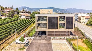 A modern building with a flat roof, large windows, and a paved entrance. - Cosy apartment for 2 people with A/C, WIFI, TV, balcony and panoramic view (Stabio)