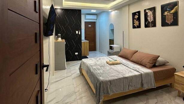 Un dormitorio moderno con una cama grande, un armario, un escritorio y un televisor instalado en la pared.