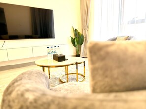 Una sala de estar con un sofá, una mesa de centro con botellas de agua, un televisor y una planta.