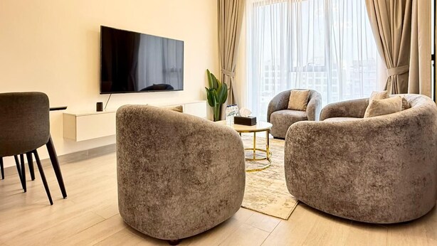 Una sala de estar moderna con un televisor de pantalla plana, dos sillones mullidos, una mesa de centro y un mueble bajo minimalista.