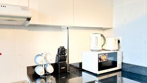 Una cocina moderna con microondas, hervidor y bloque de cuchillos.