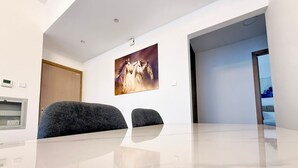 Una sala de conferencias moderna con una mesa de mármol, dos sillas grises, un termostato instalado en la pared y un cuadro grande de caballos.