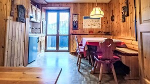 Een houten interieur met een eethoek, keuken en uitzicht door een glazen deur.