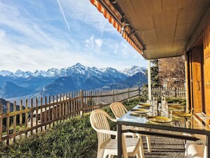 Een eettafel met uitzicht op de bergen, een houten omheining en een overdekt terras.