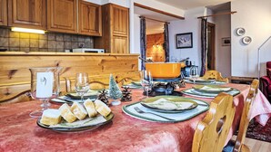 Un comedor con una mesa de madera dispuesta para una comida, con platos, vasos y un centro de mesa decorativo.