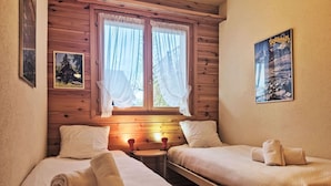 Una habitación acogedora con dos camas, una mesita y una ventana con cortinas.