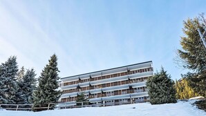 Et hotel med flere etager og balkoner, omgivet af sneklædte træer.