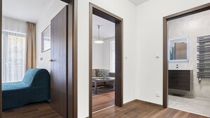 A hotel room with a wooden floor, a bed, a desk, and a bathroom with a mirror and towel rack.