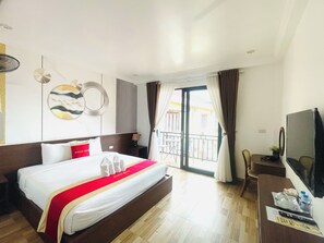 A hotel room with a bed, a desk, a TV, and a balcony with curtains. - VangVieng Avenue Hotel (Vang Vieng)