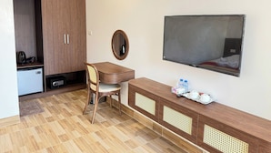 A hotel room with a wooden desk, a chair, a small kitchenette, a mirror, and a TV mounted on the wall. - VangVieng Avenue Hotel (Vang Vieng)