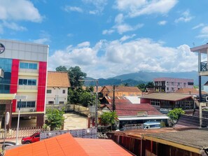 A multi-story building with a red and white facade, a flat roof, and a visible sign for a business. - VangVieng Avenue Hotel (Vang Vieng)