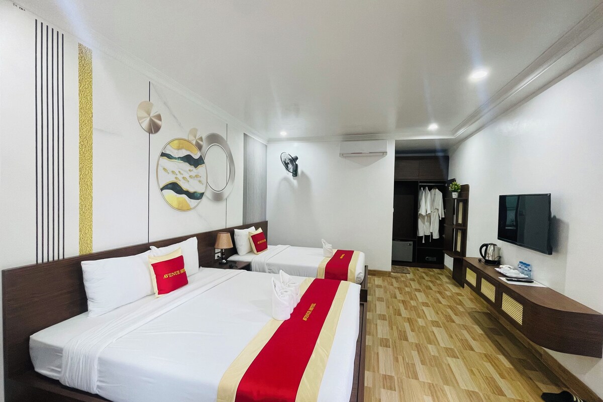 A hotel room with two beds, a TV, a wardrobe, and a mirror.