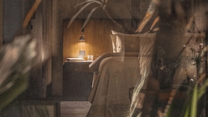 Une pièce faiblement éclairée, avec un lit, une table de chevet et une lampe.