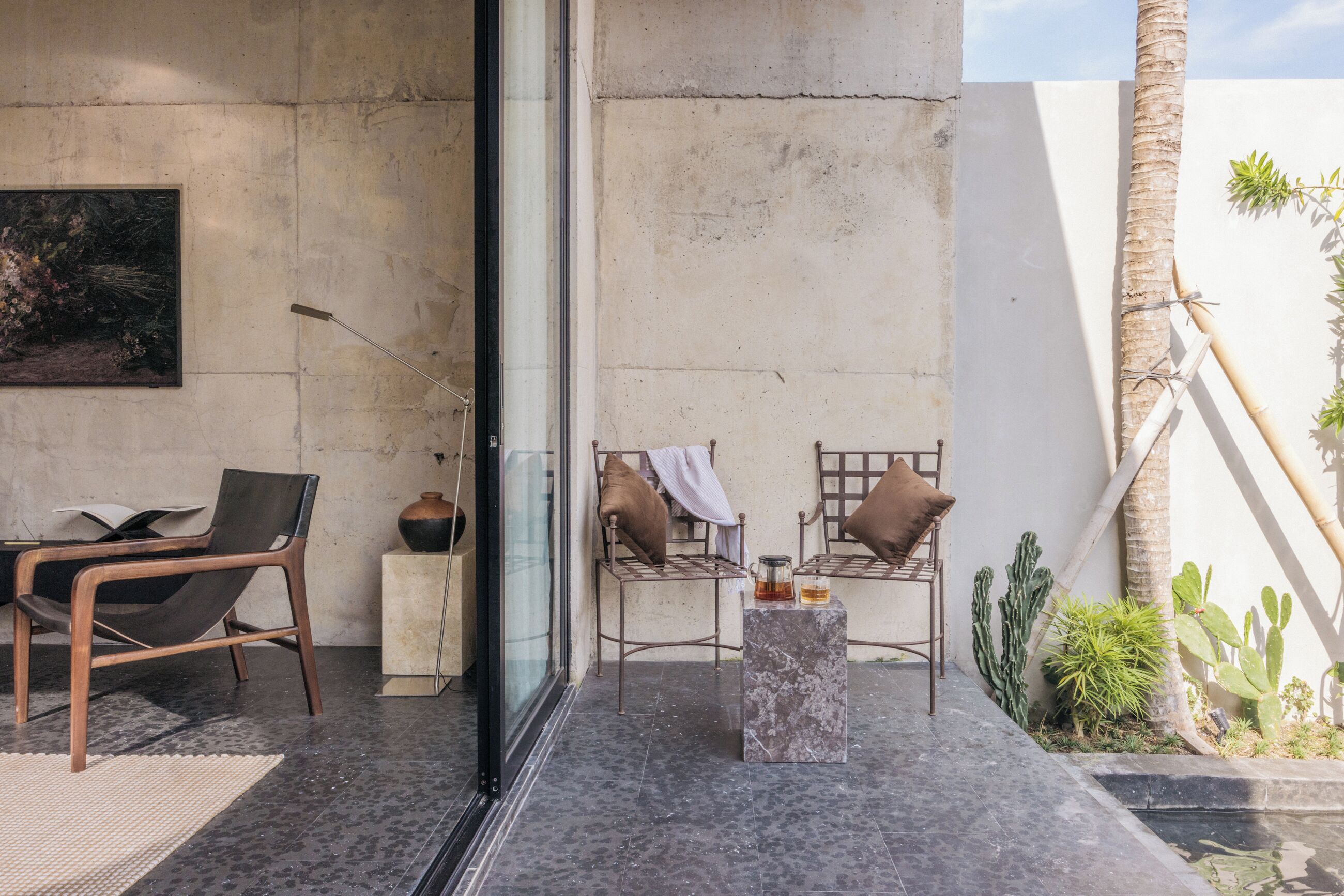 A modern outdoor seating area with two metal chairs, a small table, and a glass partition.