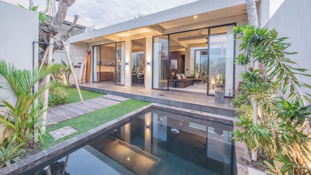 Une maison moderne dotée d’une piscine, de portes vitrées et d’un jardin bien entretenu.