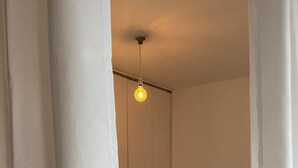 Een kleine, eenvoudig ingerichte kamer met een enkel bed, een nachtkastje en een deur naar een andere kamer.