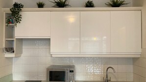 Een keuken met witte kastjes, een magnetron, een spoelbak en een zwart aanrecht.